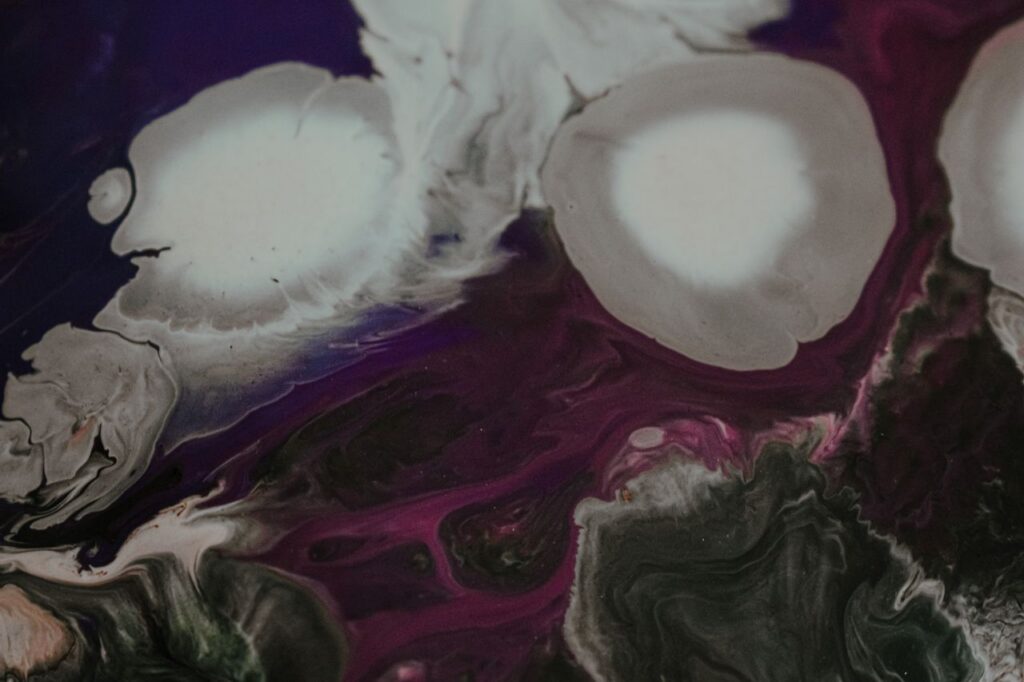 Top view of acrylic painting representing big stains and curved lines of mixed paints